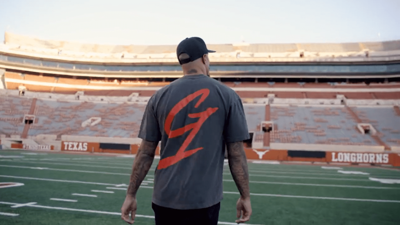 Kenny Vaccaro faces away from the camera as he walks across the Longhorn's stadium, the G1 logo is visible on the back of his shirt