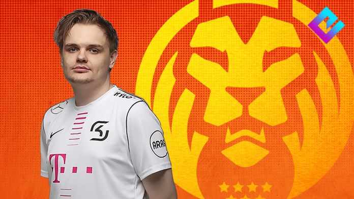 William “UNF0RGIVEN” Niemien stands in his team jersey against an orange background featuring the MAD Lions logo