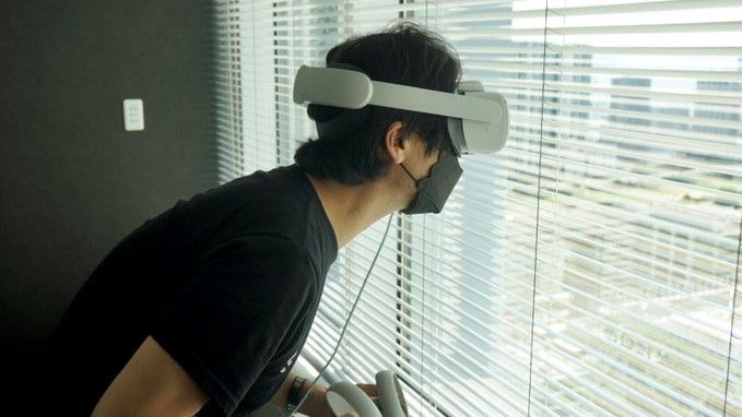 Kojima looking out of a window with a headset on, for science.