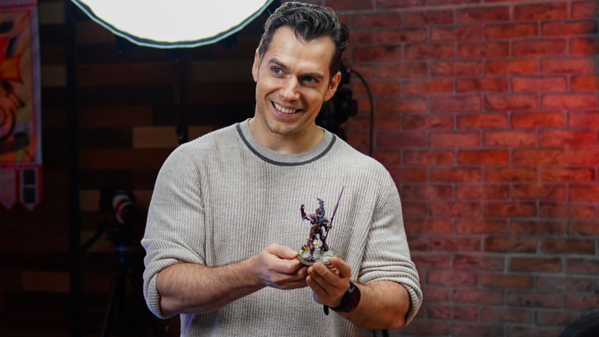 Henry Cavill holding a Warhammer figure.