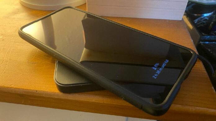 A Samsung S21+ on a wireless charger next to a bedside table