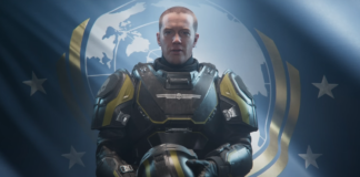 A helldiver stands, patriotic in front of a Super Earth flag, while holding a helmet in Helldivers 2.