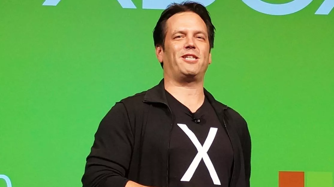 Phil Spencer giving a talk on stage, wearing a t-shirt with an